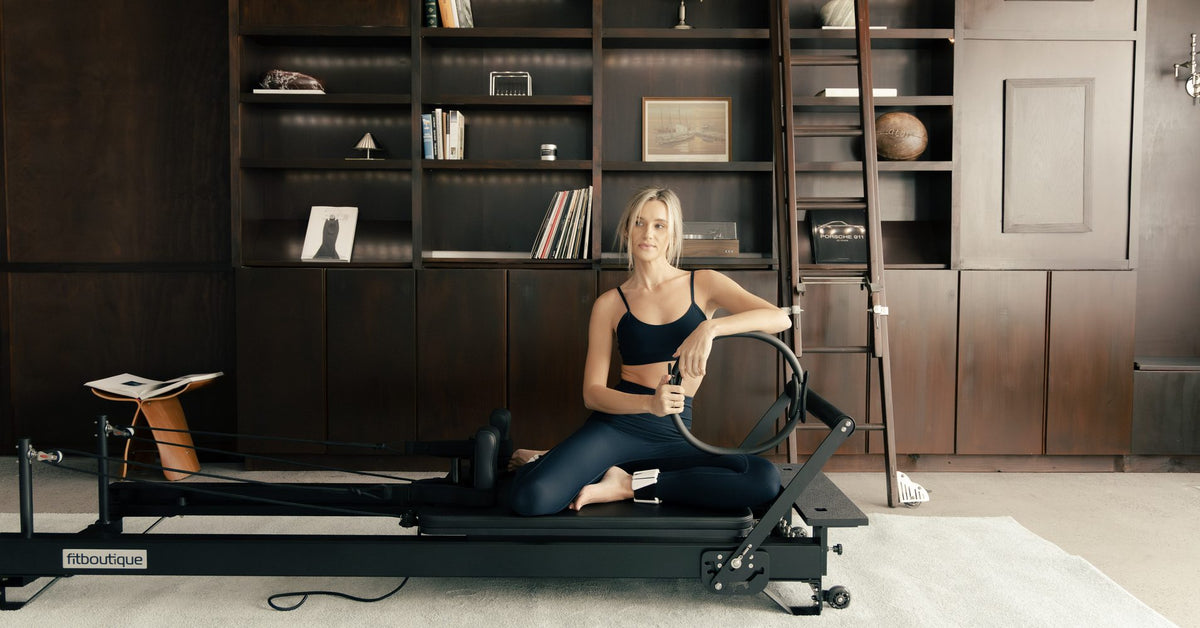 Seated with a Pilates ring on a FitBoutique reformer during class
