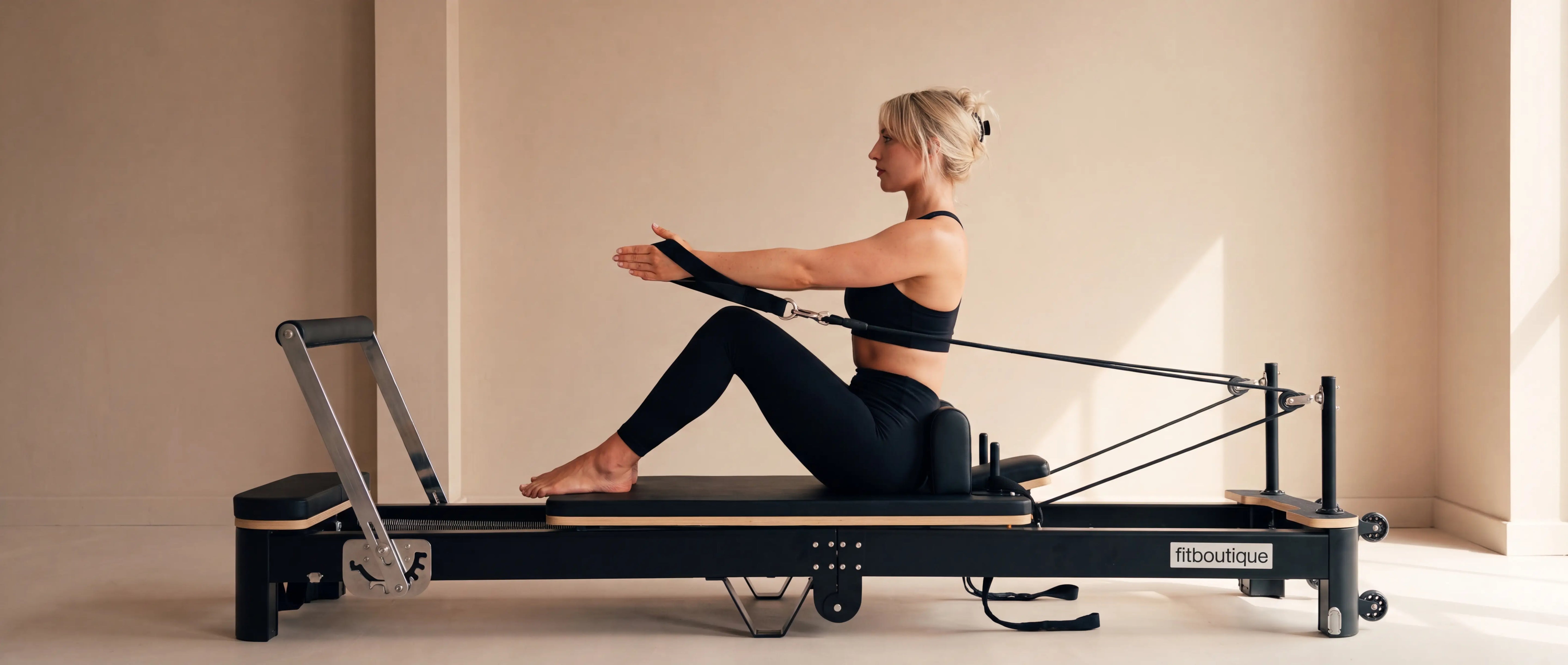 Woman lying on the FitBoutique Ivory reformer, also known as a reformer bed