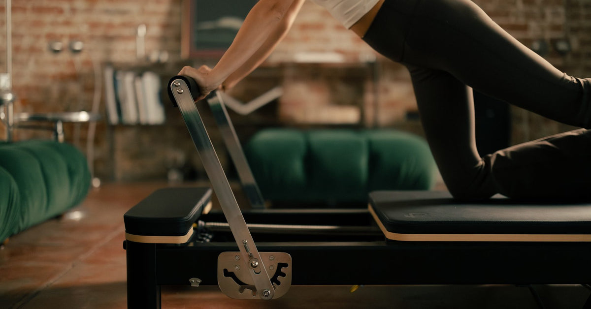 Foot pressing the footbar during reformer Pilates footwork on a FitBoutique reformer