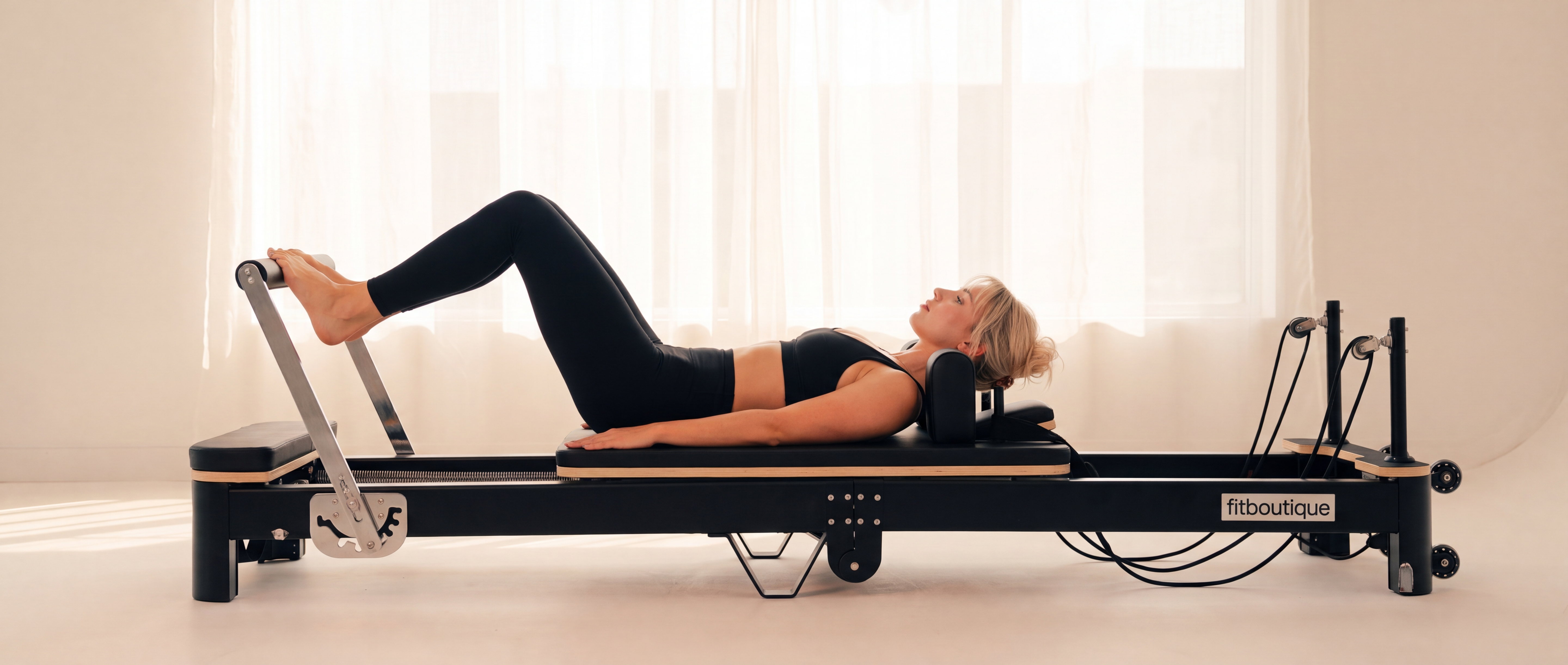 Woman on the FitBoutique Ivory reformer machine at home
